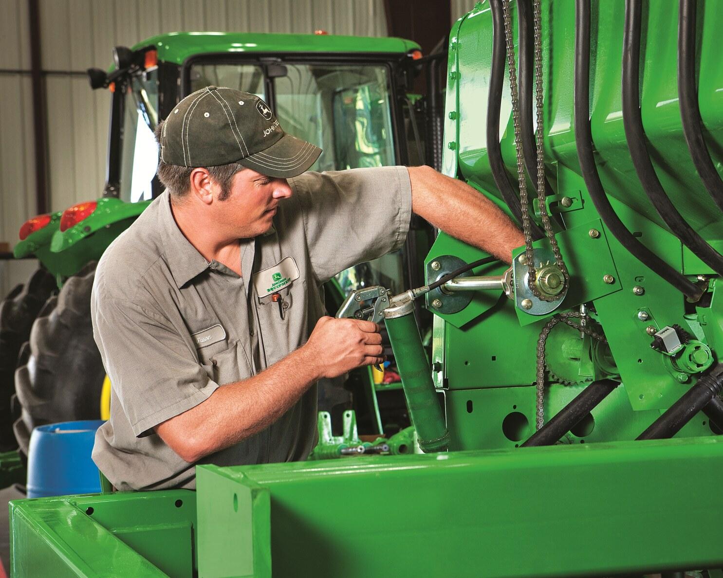 A service technician inspects a John Deere tractor.