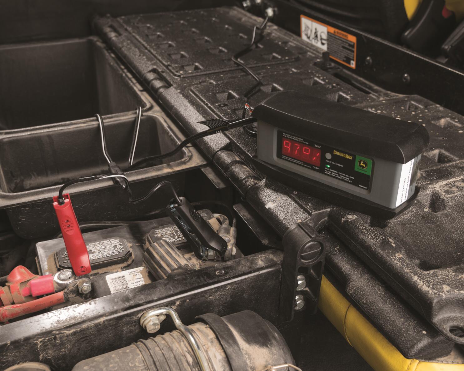 A service technician checks the battery power level on a John Deere tractor.