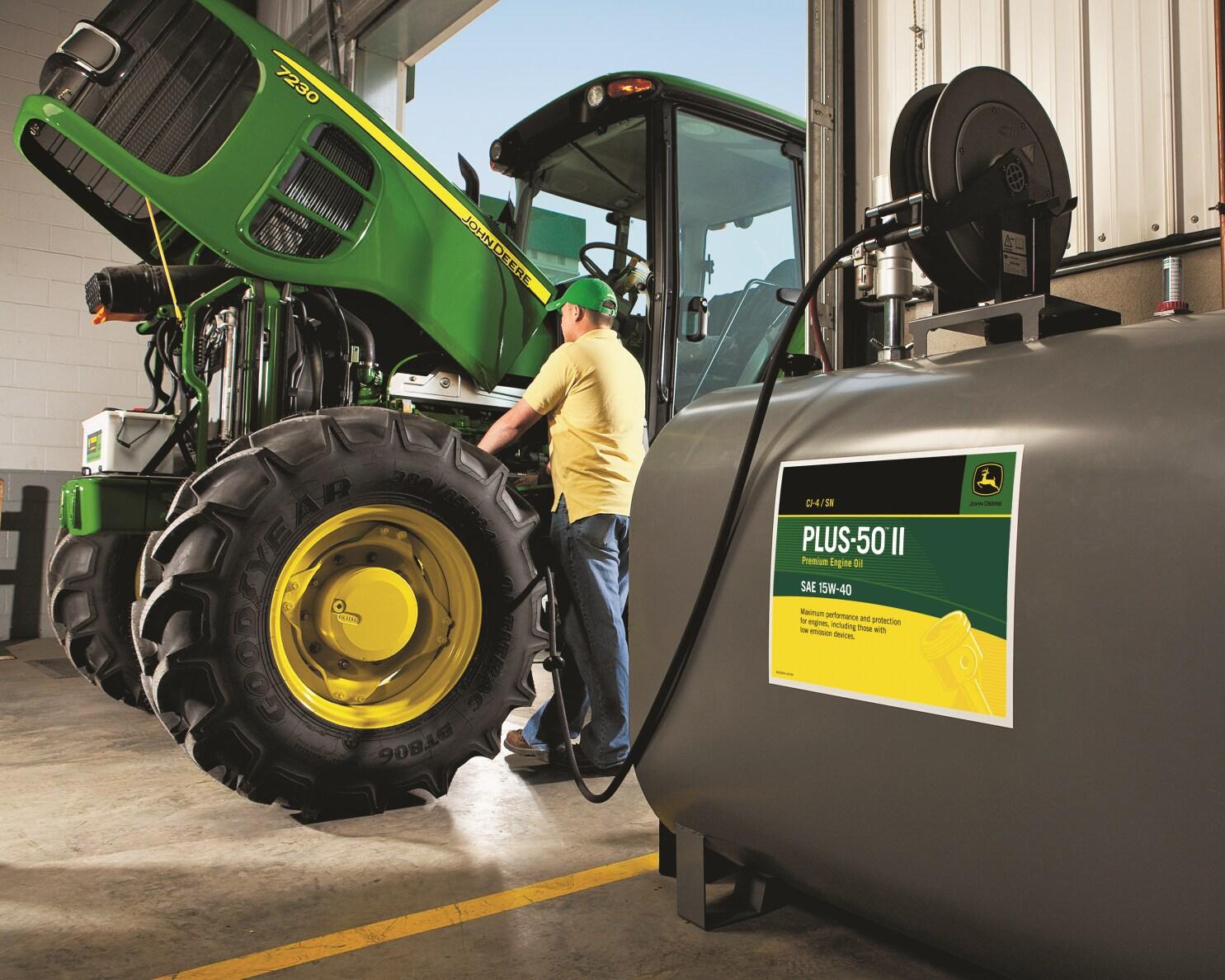 A service technician changes the oil in a John Deere tractor.