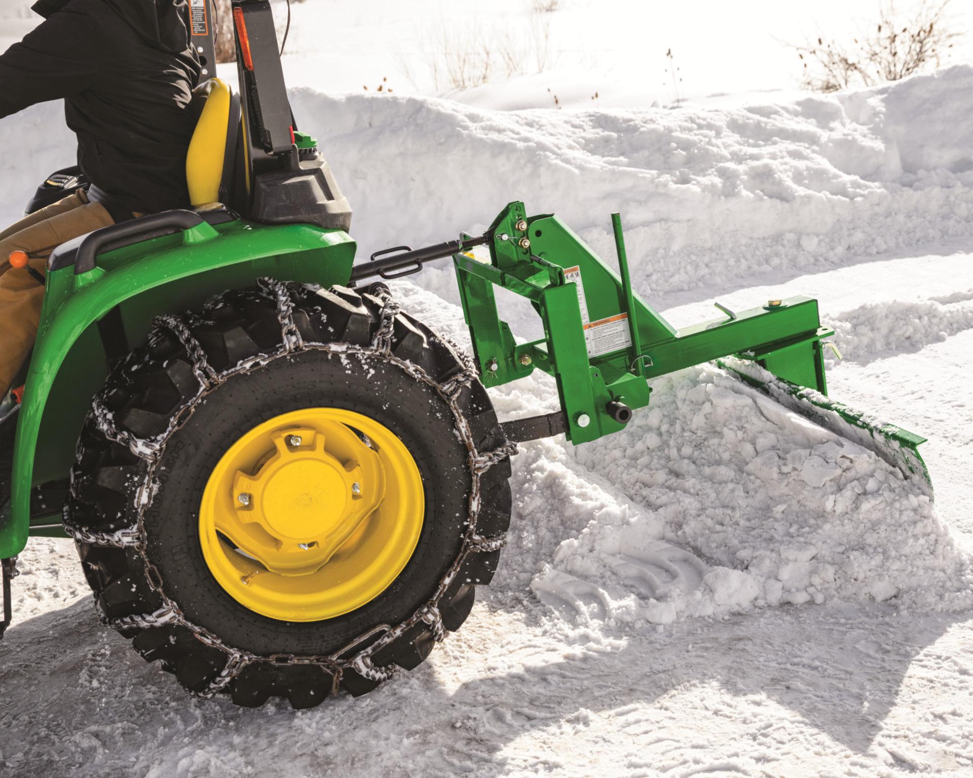 A rear blade attachment on a John Deere compact utility tractor.