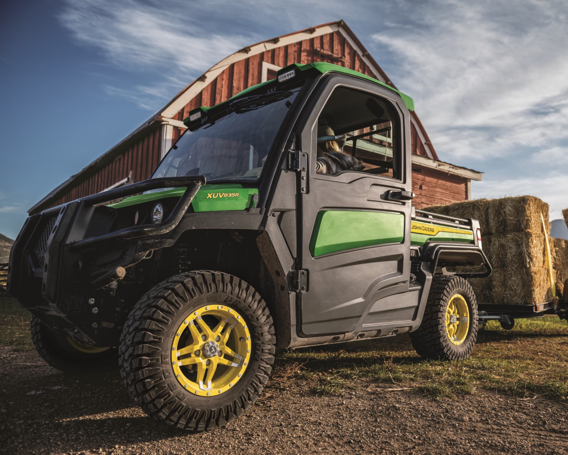 A Gator gas powered UTV in front of a red barn.